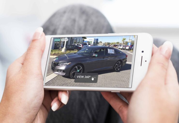 A woman using a smartphone to view a car image, blending technology with automotive interest.